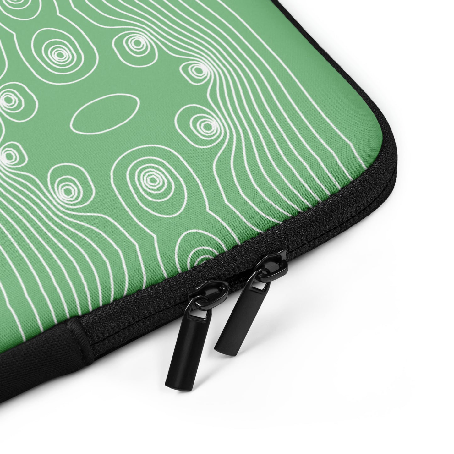 Eine Nahaufnahme einer grünen Kaeffe Art Laptoptasche – ε mit schwarzem Reißverschluss und zwei Reißverschlussanhängern. Die Hülle aus wasserfestes Material weist ein weißes, abstraktes lineares Muster auf, das an Höhenlinien erinnert, die man häufig auf topografischen Karten findet. Der Hintergrund ist sauber und weiß.